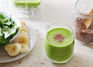 Easy Flax Seed Smoothie Overhead shot of green flax seed smoothie in a drinking glass with brown flax seeds sprinkled on top