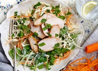 Mint Salad With Pomegranate Chicken Salad in white dish with pieces of chicken, cheese and lots of mint leaves