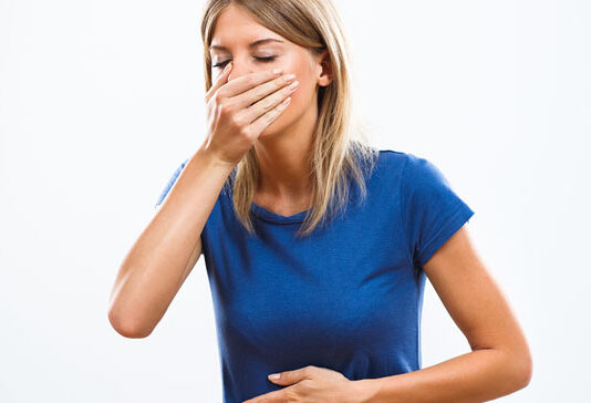 Nausea Distressed young woman with eyes closed with one hand over her mouth and the other over her stomach as if about to vomit