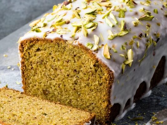 Pistachio and Lime Cake Pistachio cake with white icing and green slivers of pistachios on top