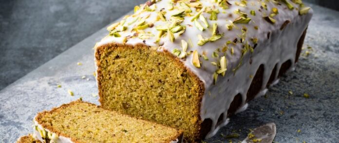 Pistachio cake with white icing and green slivers of pistachios on top