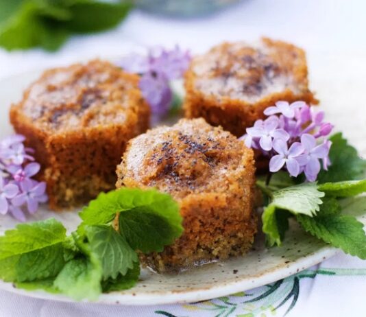 Lemon Balm Poppy Seed Honey Cake Three small round Lemon Balm Poppy Seed Honey cakes on a white dish with lemon balm and purple flower garnishments