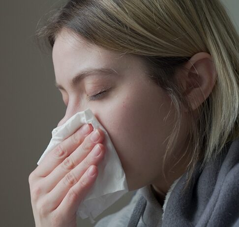 Common Cold Young woman with cold holds a tissue to her nose